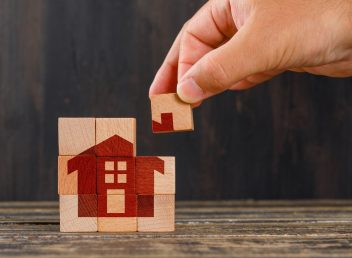 Stay at home concept on wooden background side view. hand holding wooden cube.